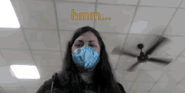 a woman wearing a mask with a ceiling fan in the background