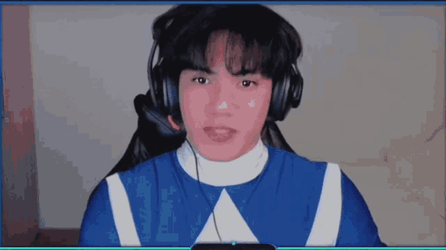 a young man wearing headphones and a blue shirt with a white triangle on it