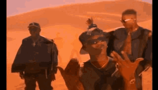 a group of men are standing in front of a desert .