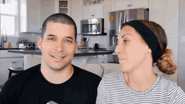 a man and a woman are looking at each other in the kitchen