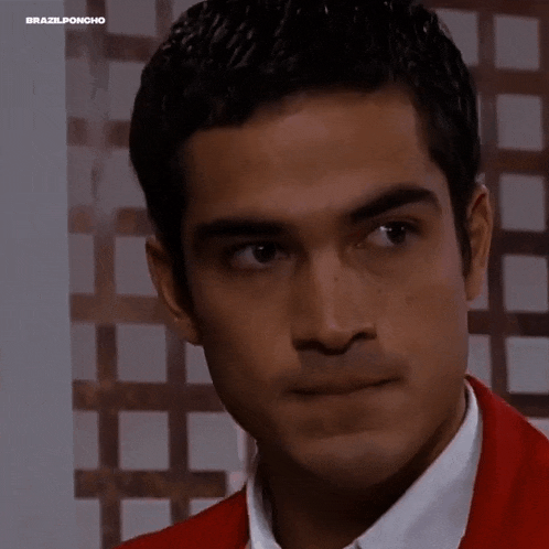 a close up of a man wearing a red jacket and white shirt making a funny face .