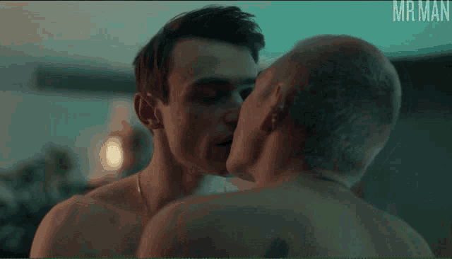 two shirtless men kissing in front of a green screen that says mr. man