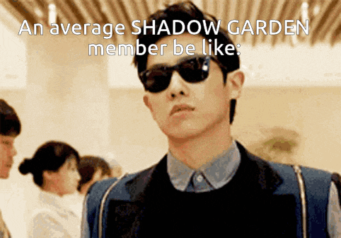 a man wearing sunglasses stands in front of a sign that says " an average shadow garden member be like "