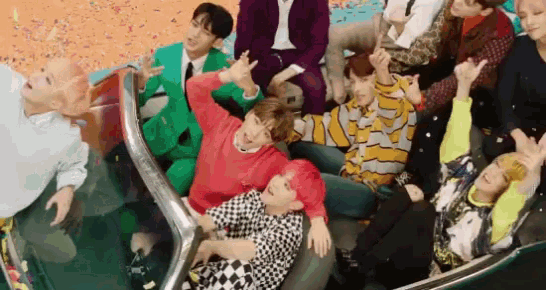 a group of people are sitting in a convertible car with their hands in the air .