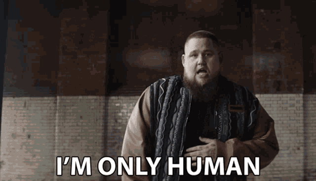 a man says i 'm only human while standing in front of a brick wall