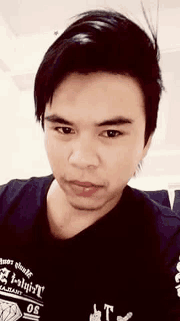 a close up of a man 's face wearing a black shirt and looking at the camera .