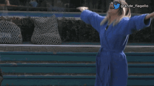 a woman in a blue robe is standing in front of stairs with her arms outstretched and the words grande flagello above her