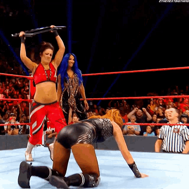 two women are wrestling in a ring with a referee watching .