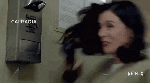 a woman is standing in front of a telephone and her hair is flying in the air .