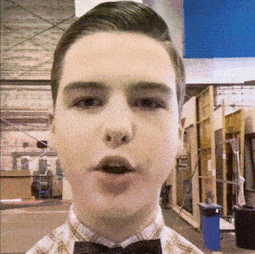 a young man wearing a plaid shirt and bow tie