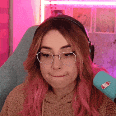 a girl with pink hair wearing glasses and headphones making a funny face