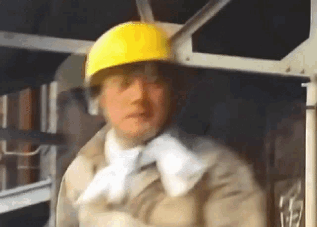 a man wearing a hard hat and gloves is standing in a dark room .