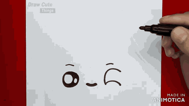 a person is drawing a face on a piece of paper with a pen