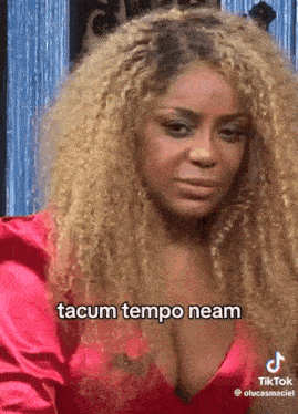 a woman with blonde curly hair is wearing a red dress and has a very large cleavage .