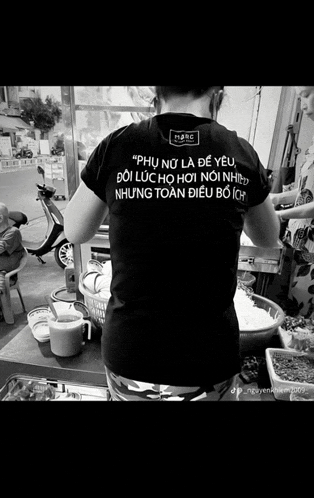 a black and white photo of a woman wearing a t-shirt that says " phụ nữ là đề yêu "