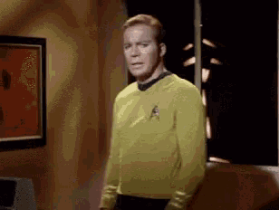 a man in a yellow star trek uniform is standing in a room .
