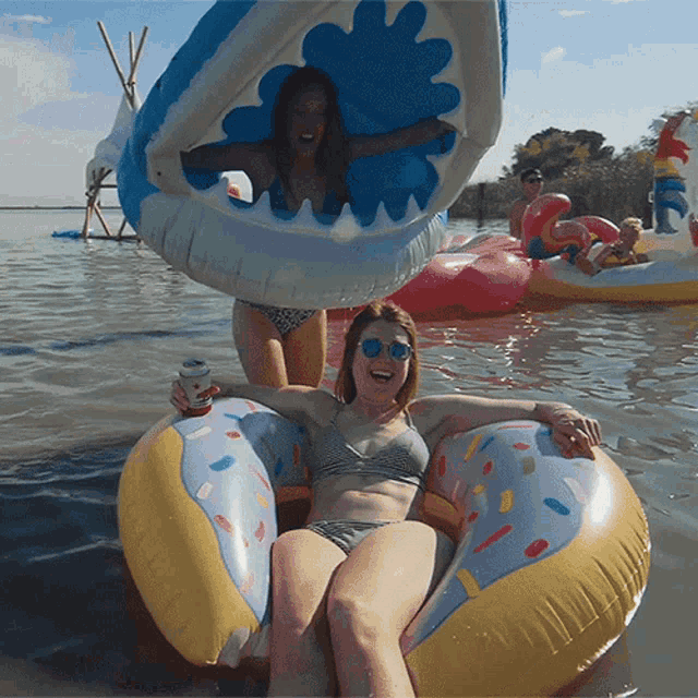 a woman in a bikini sits in a donut shaped raft in the water