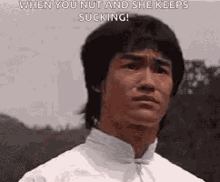 bruce lee is making a funny face while looking at the camera .