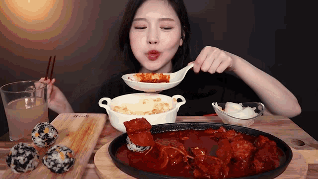 a woman is eating a spoonful of food from a bowl