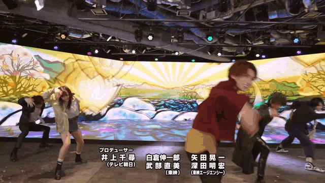 a group of people are dancing in front of a large screen that says producer on it