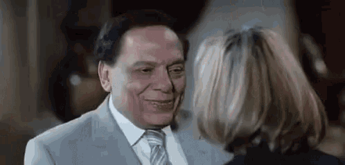 a man in a suit and tie is smiling at a woman in a black jacket .