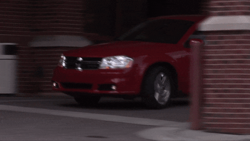 a red dodge car is parked in a parking lot