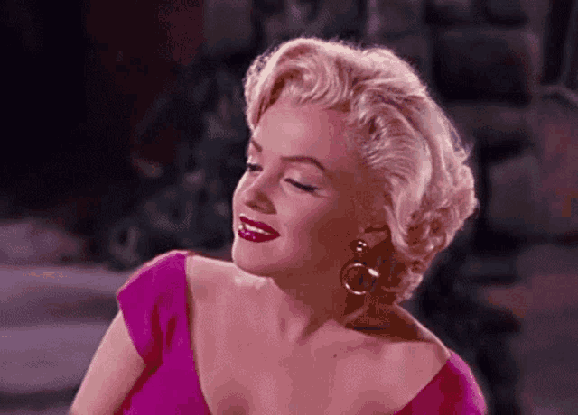 a woman with blonde hair is wearing a pink dress and earrings