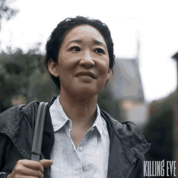 a woman is walking down a street with a killing eye logo on her jacket