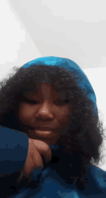 a woman with curly hair is wearing a blue scarf around her head