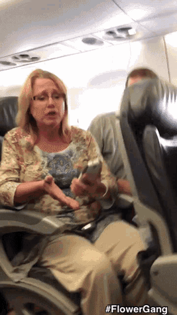 a woman sits on an airplane looking at her phone with the hashtag flowergang