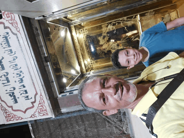 a man and a boy are posing for a picture in front of a sign that says ' elevator ' on it
