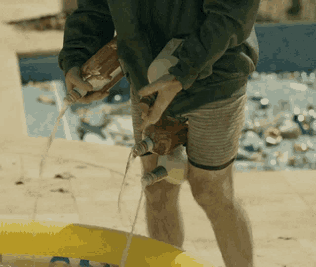 a man is pouring liquid from a bottle into a yellow pool