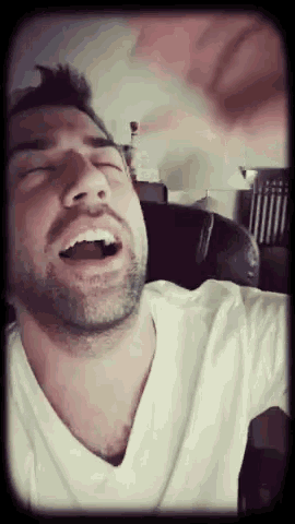 a man in a white shirt is yawning with his mouth open