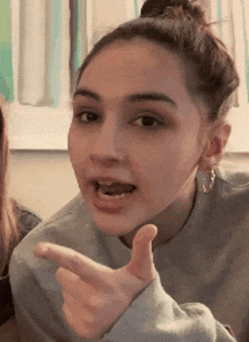 a girl is giving a thumbs up sign with her mouth open