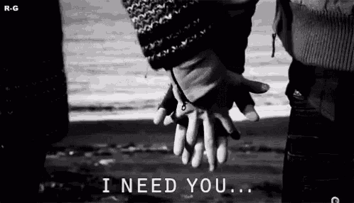a black and white photo of a couple holding hands on a beach .