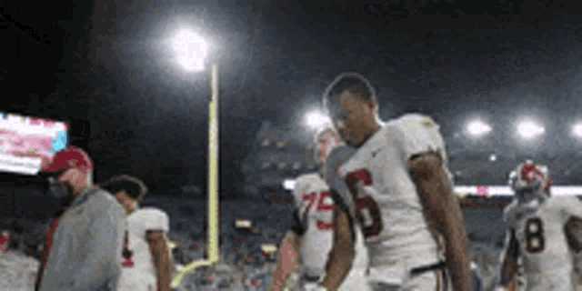 a group of football players are walking off the field at night