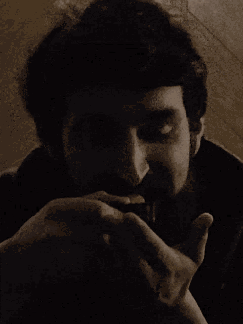 a man with a beard is smoking a cigarette in a dark room