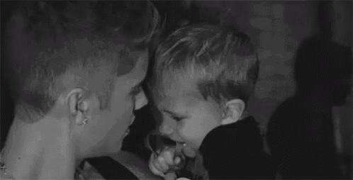 a man is kissing a little boy on the cheek .