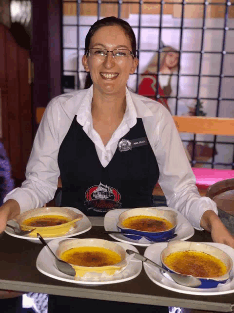 a woman wearing an apron that says ' captain ' on it is holding a tray of food
