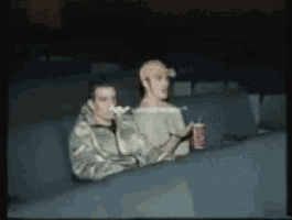 two men sitting in a theater watching a movie