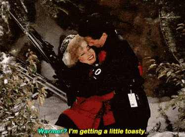 a man and woman hugging in the snow with the man saying warmer i 'm getting a little toasty