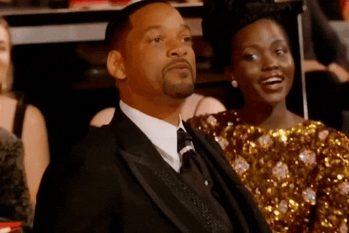a man in a suit is sitting next to a woman in a gold dress .