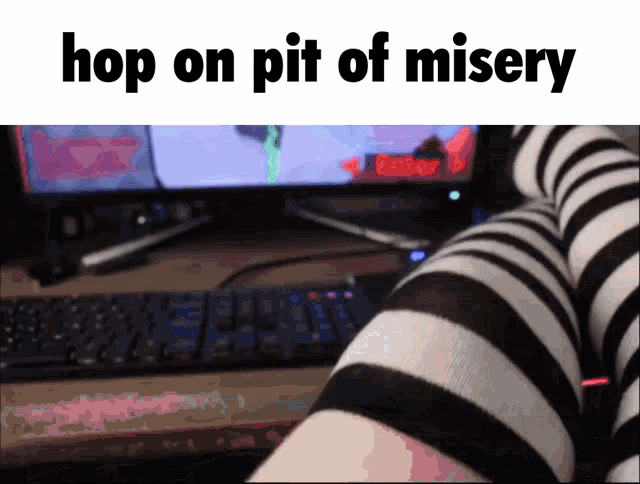 a person wearing striped knee high socks sits in front of a computer monitor