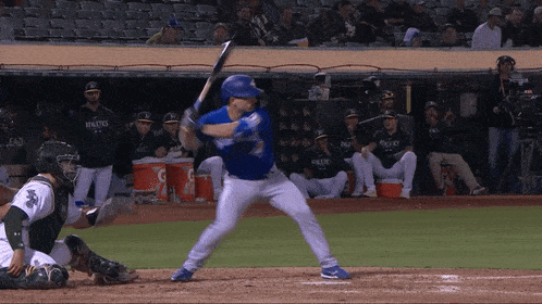 a baseball player is swinging at a pitch while a catcher looks on