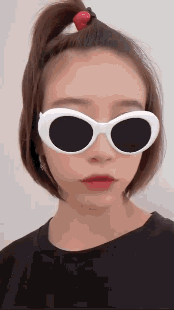 a woman wearing sunglasses and a ponytail with a strawberry in her hair