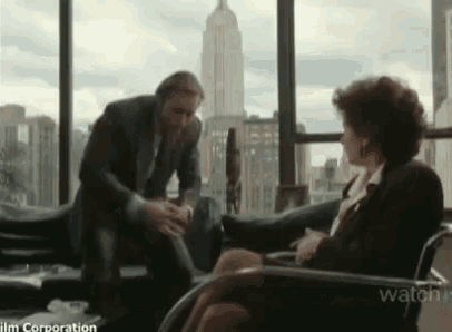 a man in a suit is talking to a woman in a chair .