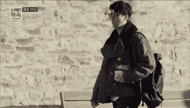 a man wearing glasses and a backpack is walking in front of a tvn logo