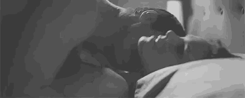 a black and white photo of a man and a woman laying on a bed .