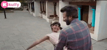 a man is holding a little girl in his arms and they are dancing on the sidewalk .
