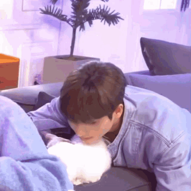 a man in a denim jacket is kissing a white cat on the nose